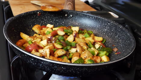 mixed vegetable and potatoes cooking in frying pan at home, closeup