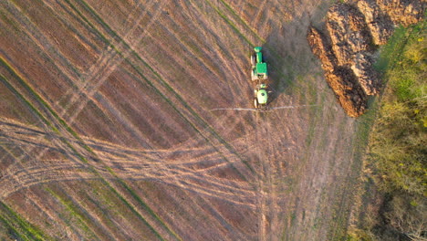 Aerial-straight-down-shot-of-industrial-tractor-spraying-fertilizer-on-field
