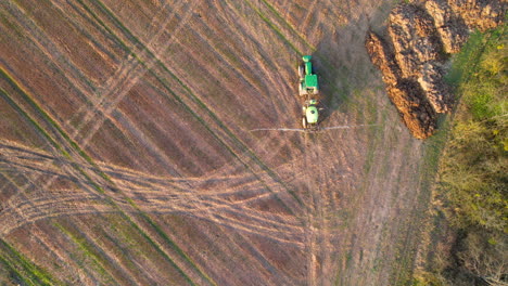 Toma-Aérea-Recta-Hacia-Abajo-Del-Tractor-Industrial-Rociando-Fertilizante-En-El-Campo