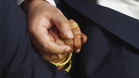 close-up of a couple's hands, adorned with traditional indian jewelry and henna