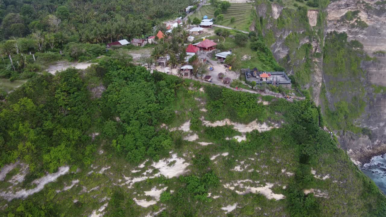 carretilla aérea en el punto de vista de la playa de kelingking, área de estacionamiento y mini mercados en un acantilado empinado en la isla de nusa penida, bali