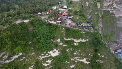 carretilla aérea en el punto de vista de la playa de kelingking, área de estacionamiento y mini mercados en un acantilado empinado en la isla de nusa penida, bali