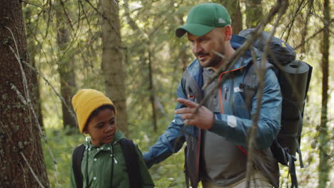 man hiking in woods with little son