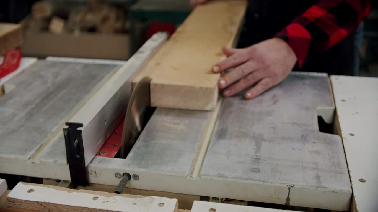 el maestro corta una tabla de madera con una sierra circular en el taller de carpintería de un pequeño fabricante de muebles. cámara lenta.