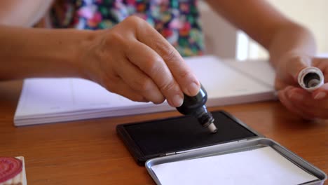 Woman-Pouring-Black-Ink-To-Stamp-Pad-On-The-Office-Table