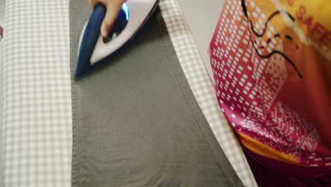 Closeup-of-a-woman-ironing-clothing-by-stream-iron-on-board-at-home