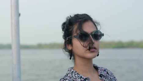 close-up shot of an indian woman with sunglasses looking away and then turns towards the camera