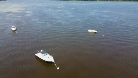 Pull-back-drone-flight-over-motorboats-on-the-Kennebec-River,-BATH