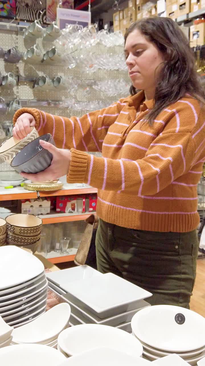 A woman is shopping for plates and bowls in a store