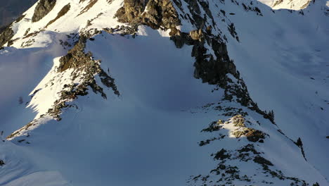 drone shot , pedestal up over a snow covered mountain to reveal a mountain background