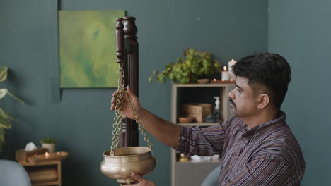 a man holding a hanging pot in a room