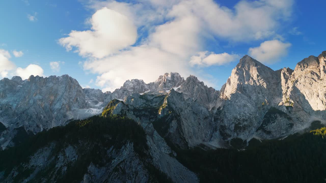 Fluffy clouds above rocky peaks of Slovenia Alps, aerial view