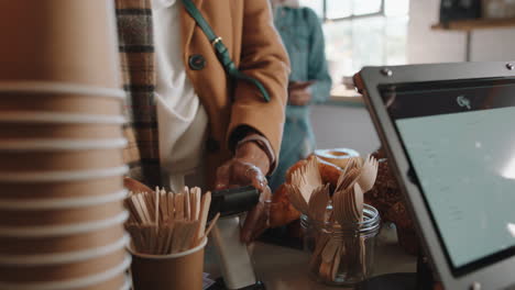 close up customer using credit card machine typing password making payment spending money in cafe