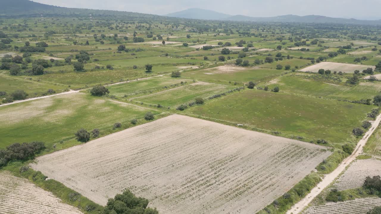 Slow Forward Drone Aerial Rise Over Dry Farmland With Green Fields on the Horizon in Mexico – Forward Ascend Shot, Midday Sunny 4K