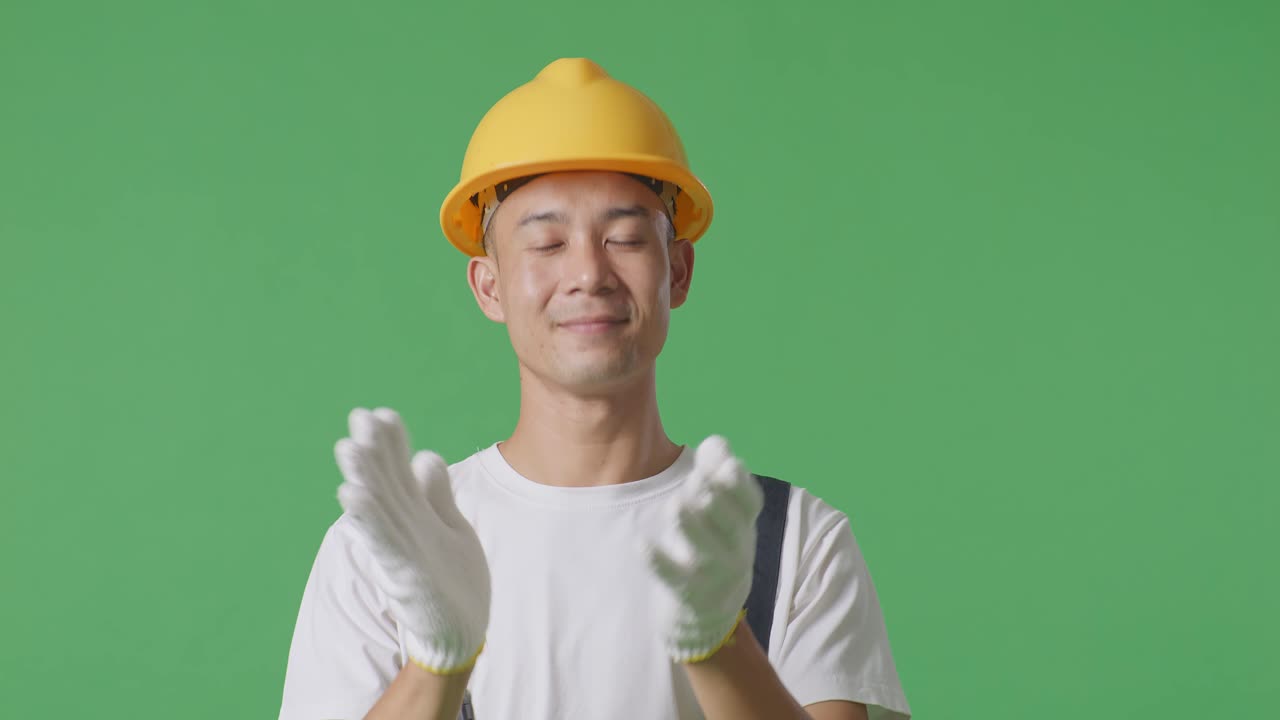 Close Up Of Asian Man Painter Wearing Safety Helmet Smiling And Clapping His Hands While Standing In The Green Screen Background Studio