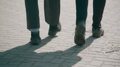 Low-angle-view-of-two-persons-walking-on-the-concrete-pavement