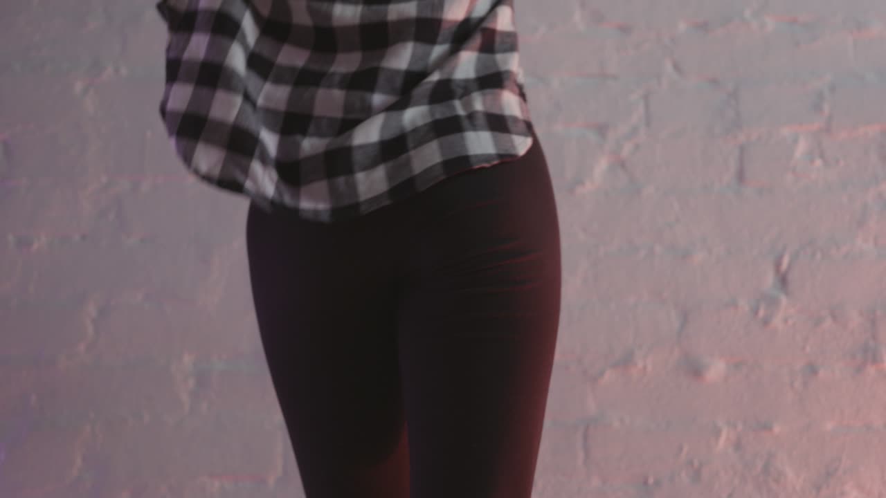 Donna che balla in camicia a quadri e pantaloni neri