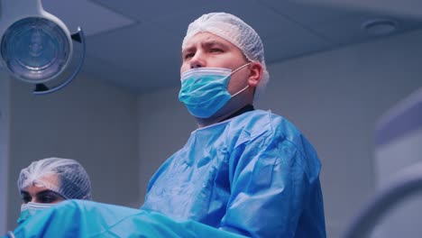 portrait of male surgeon. doctor in mask and protective uniform looking ahead seriously. surgeon and a nurse during the operation in clinic.