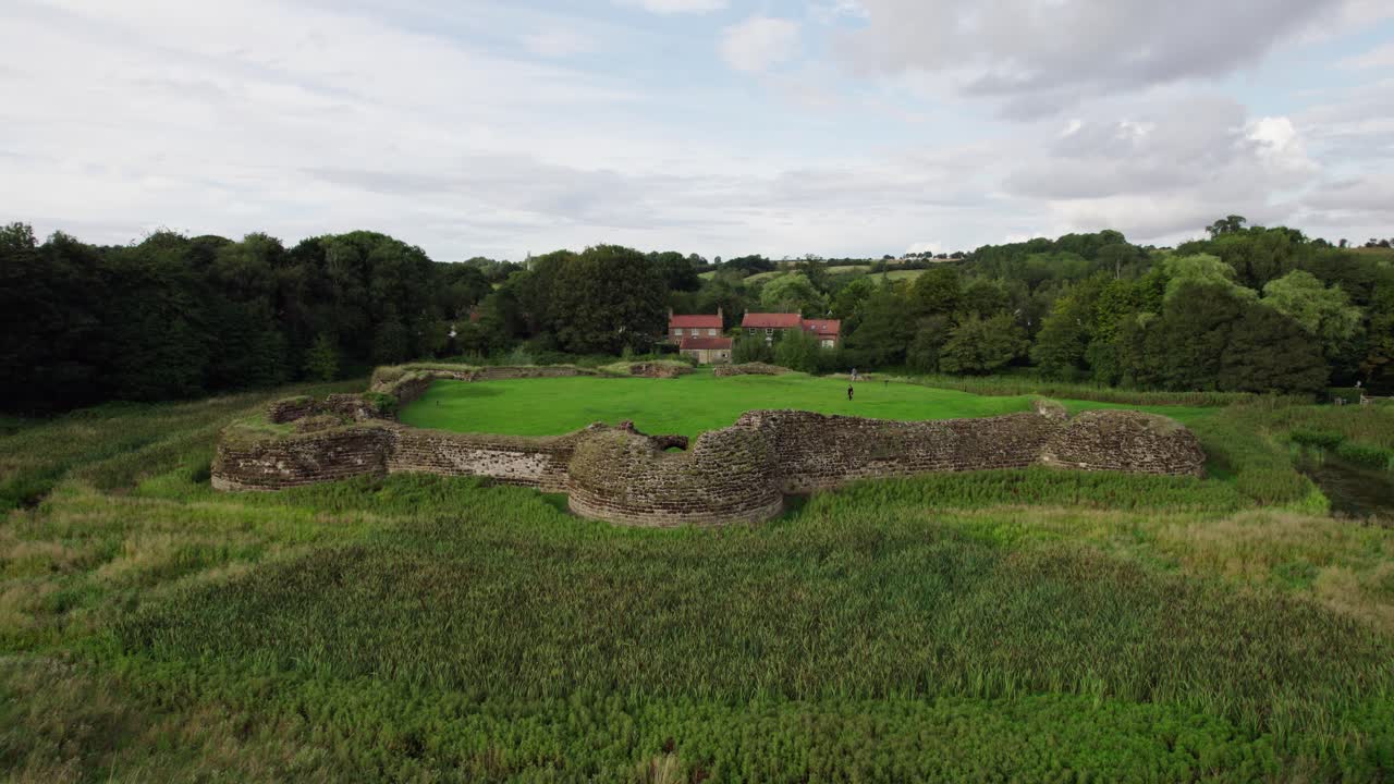 Aerial video footage of the remains of Bolingbroke Castle a 13th century hexagonal castle, birthplace of the future King Henry IV, with adjacent earthwork
