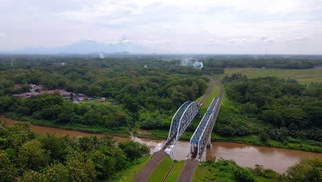 aerial view of railway bridge on the large river with view of beautiful rural landscape