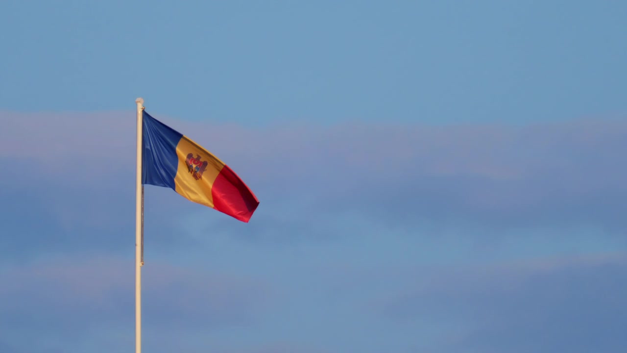 Bandiera nazionale moldava che sventola su un'alta asta contro un cielo azzurro limpido.