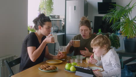 lesbian parents and little son eating breakfast at home