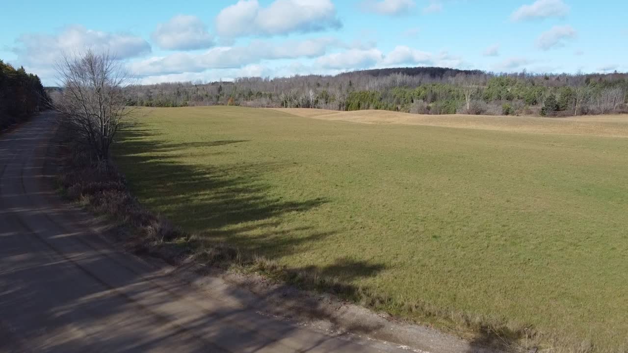 toma aérea ascendente de un campo agrícola rodeado de bosques y carreteras