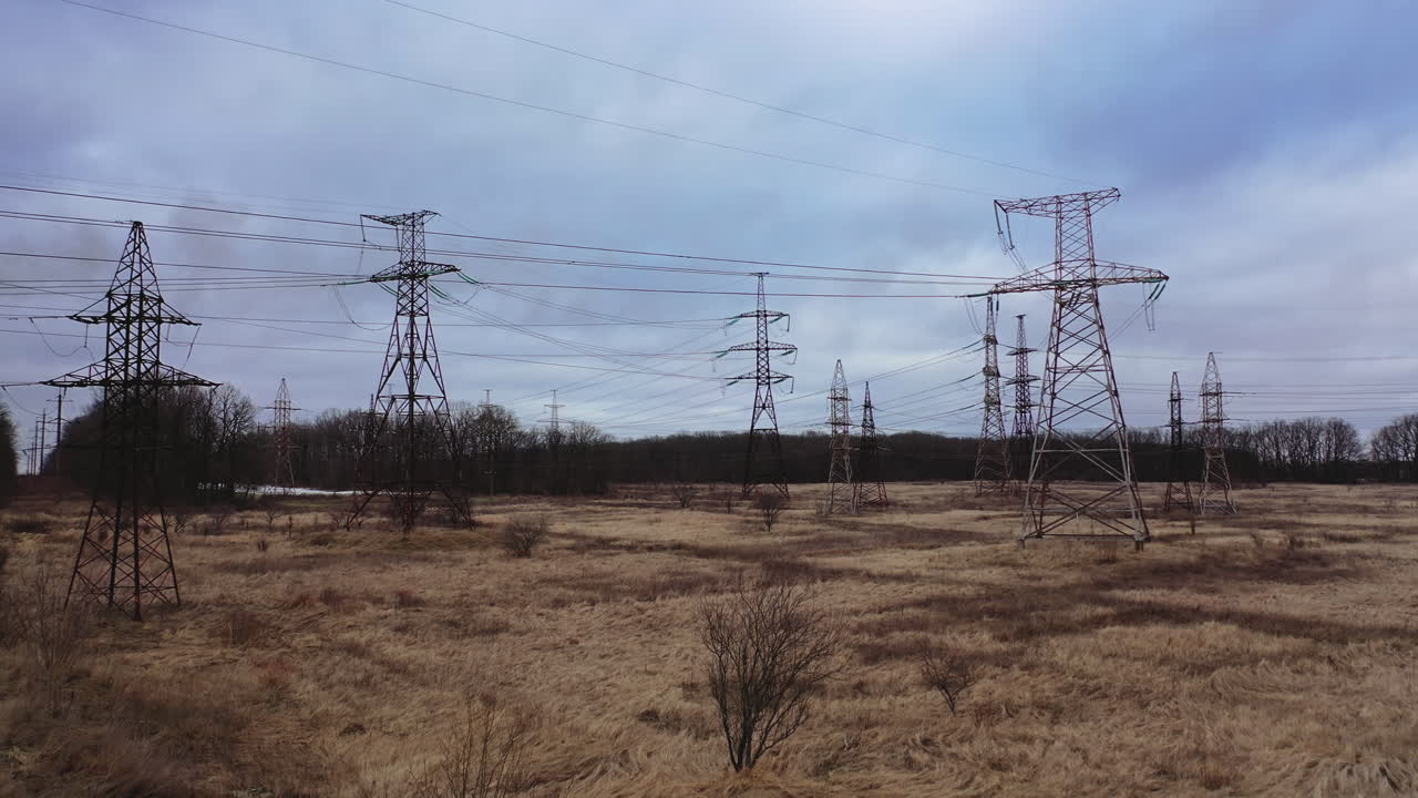 High voltage electric towers on field. Transmission power lines. High voltage power line insulators. Electric towers with electric cables stretched between them, wires with high voltage current.