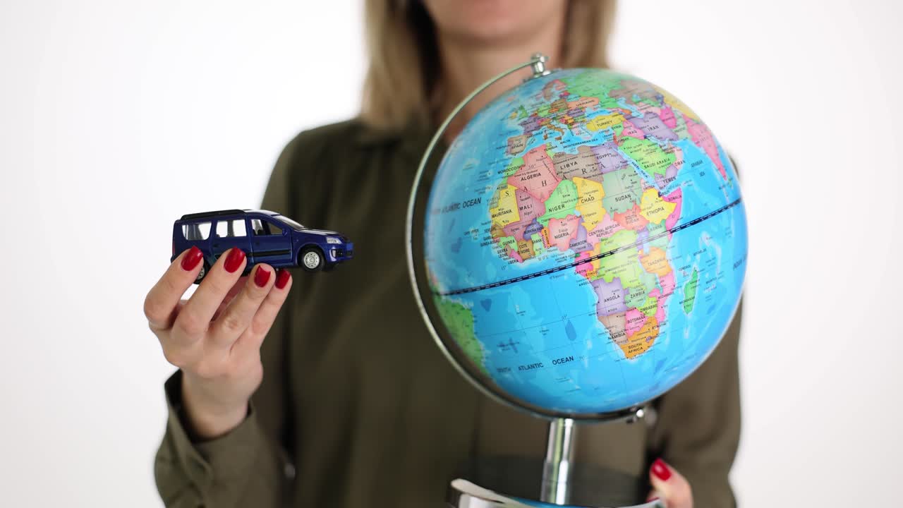 Woman holding a toy car near a globe