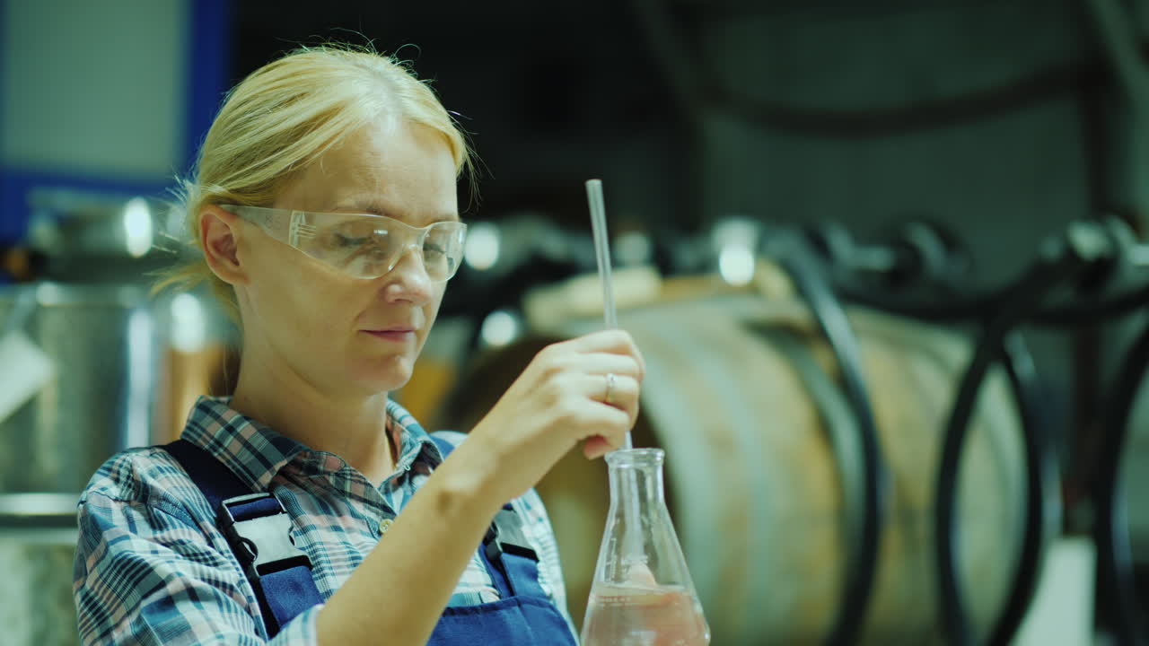 investigadora que trabaja con muestras de productos en un matraz contra el fondo de barriles de madera o