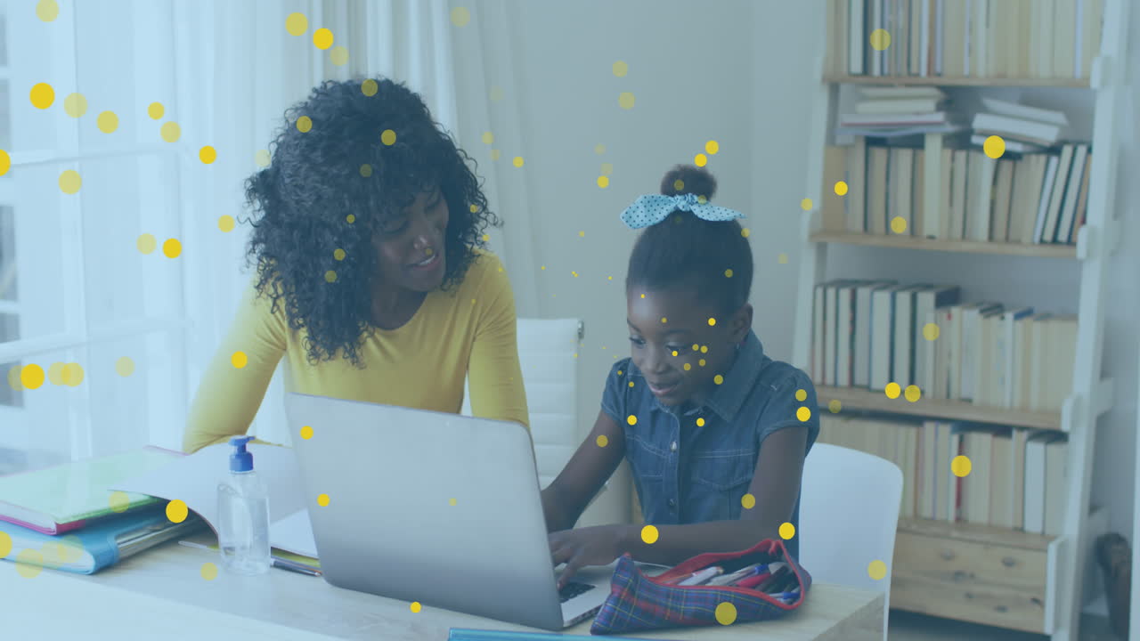 Animation of yellow spots floating over african american mother helping daughter in homework at home