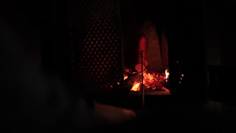 grilling a sausage on stick, in a fireplace, dark, moody, warm cottage vibe