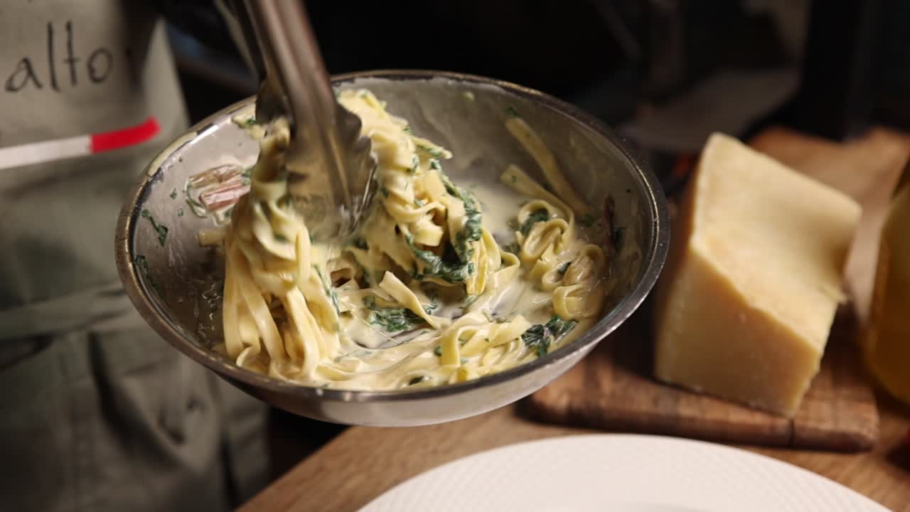 Chef che mescola pasta cremosa agli spinaci in padella