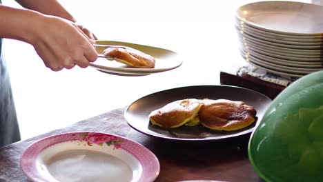 hand serving pancakes onto a plate