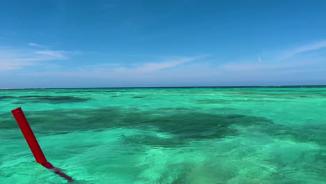 Blue-sky-meets-Turquoise-waters-as-a-red-buoy-passes-by-near-Punta-Cana,-Dominican