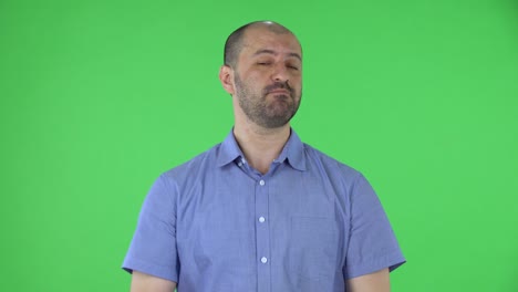 retrato de un hombre de mediana edad mirando a la cámara muestra dedos de gesto ok. hombre calvo con barba en camisa azul posando en pantalla verde en el estudio. cerca