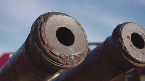 cannon tubes and muzzles covered with rust against blue sky