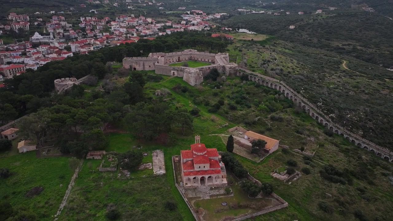 Ripresa aerea con drone in ascesa sopra la Chiesa della Trasfigurazione del Salvatore, l'acquedotto ottomano e le imponenti mura in pietra della fortezza di Niokastro vicino a Pylos in Messenia, Grecia