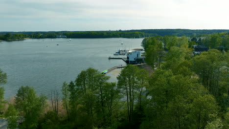 Eine-Luftaufnahme-Des-Ukiel-Sees-In-Olsztyn,-Die-Den-Jachthafenbereich-Mit-Booten-Und-Grünen-Bäumen-Hervorhebt-Und-Einen-Panoramablick-Auf-Den-See-Bietet