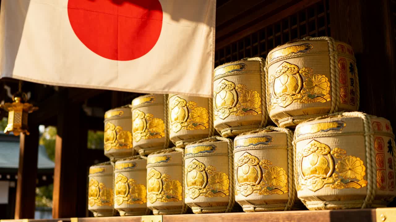 Pengambilan gambar panning bendera Jepang yang berkibar tertiup angin dan tong sake di kuil yang disinari matahari