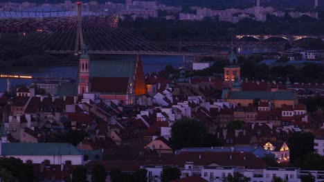 Most Swietokrzyski, Holy Cross bridge over Vistula river in background with old town Royal Castle gothic style buildings in foreground in evening, Warsaw, Drone shot