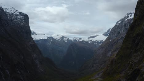 Aerial-Flight-Through-Vast-Valley-Toward-Snowy-Peaks-in-Fiordland,-New-Zealand,-South-Island