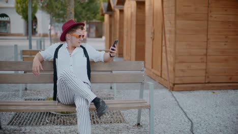 hombre usando un teléfono inteligente en un banco en una calle de la ciudad
