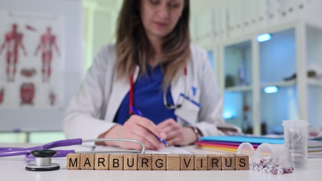Wooden blocks spell words marburg virus at stethoscope by doctor