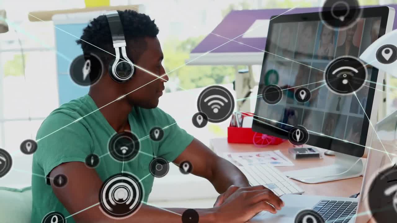 Animation of network of digital icons over african american male graphic designer using laptop