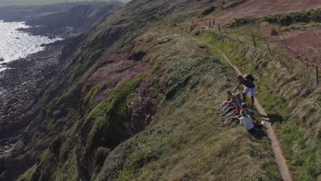 drone shot of group of friends hiking along cliffs on coastal path