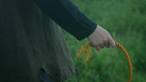 dramatic slow-motion closeup shot of hand holding nylon rope as person slowly walks outdoors.