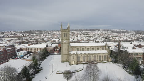 Aerial-view-of-St-Jame's-church-covered-in-snow-in-the-midlands,-Christian,-Roman-catholic-religious-orthodox-building-in-a-mainly-muslim-area-of-Stoke-on-Trent-in-Staffordshire,-City-of-Culture