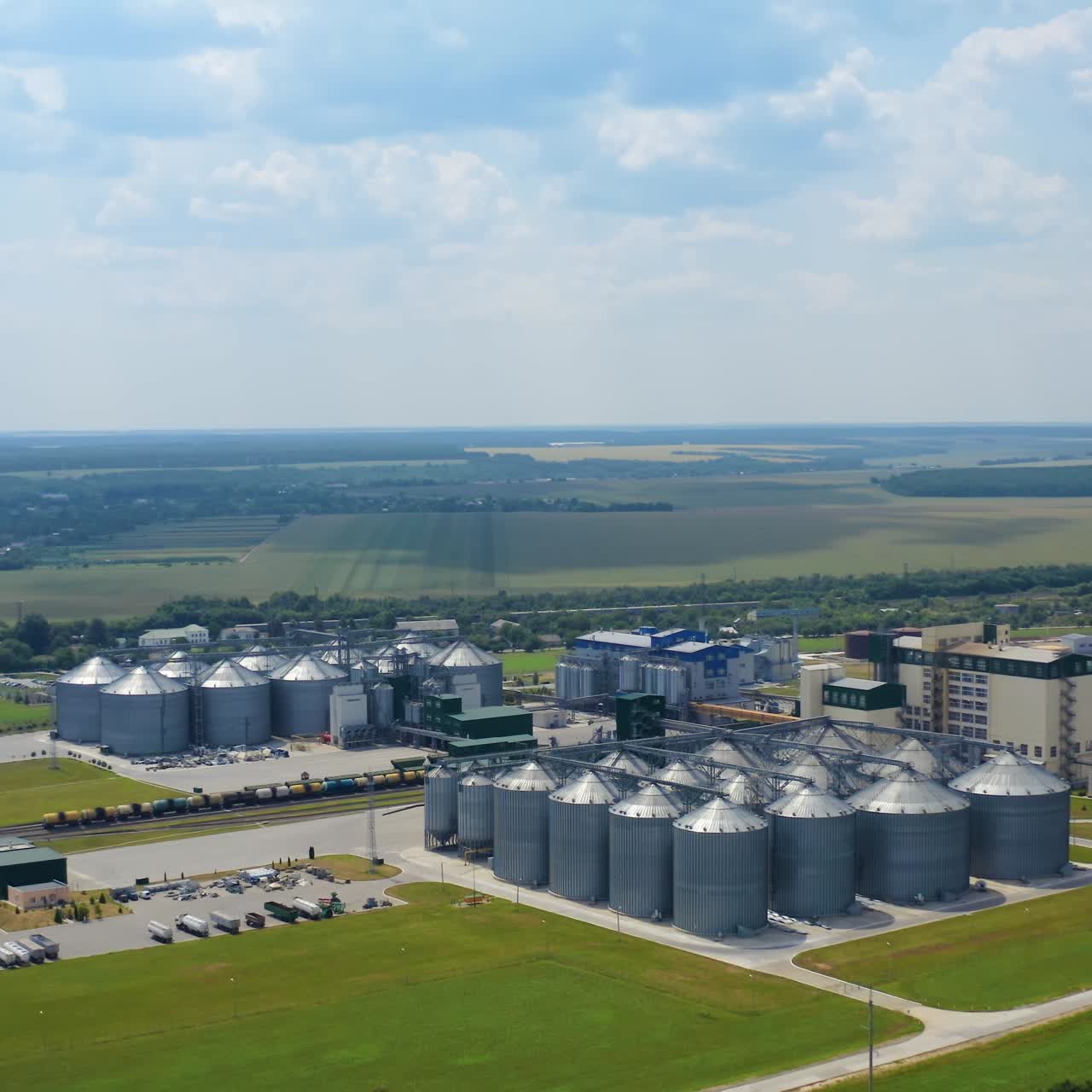 Modern granary in the countryside. Grain-drying complex with large metal elevators in rural landscape. Commercial seed silos on field. Grain terminals. Aerial view