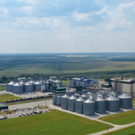 Modern granary in the countryside. Grain-drying complex with large metal elevators in rural landscape. Commercial seed silos on field. Grain terminals. Aerial view